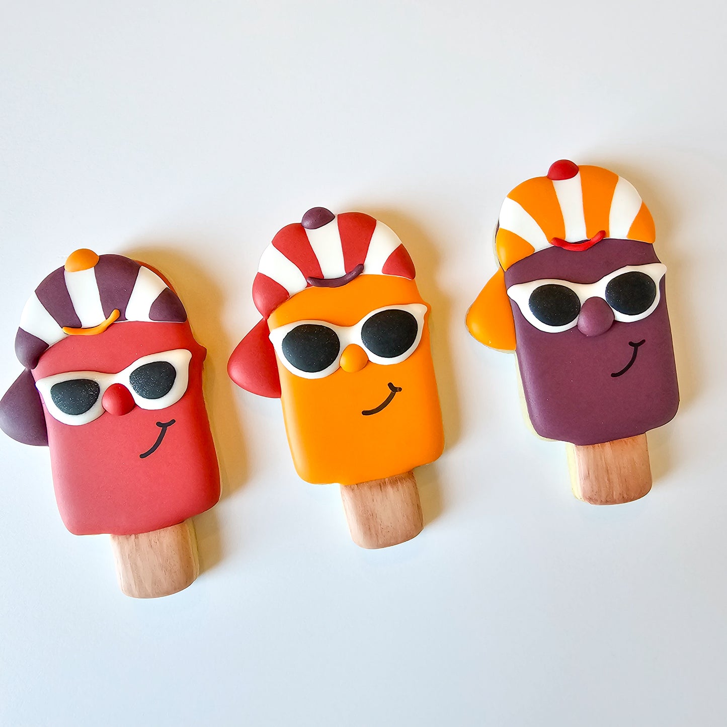 Popsicle sugar cookies wearing hats and sunglasses