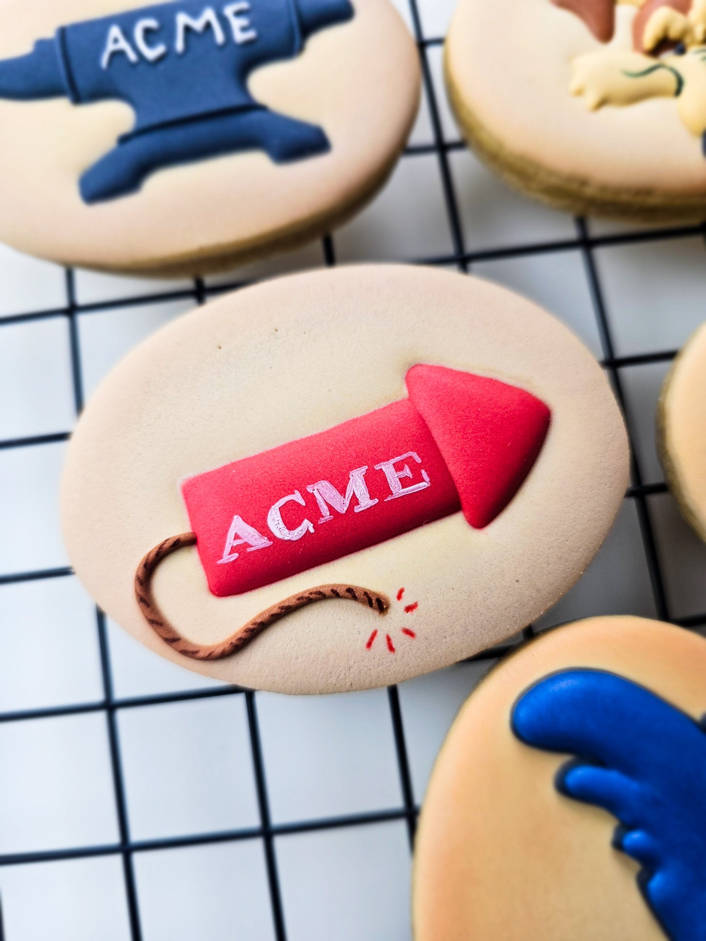 Red Acme rocket on a tan oval shaped decorated sugar cookie sitting on a black grid