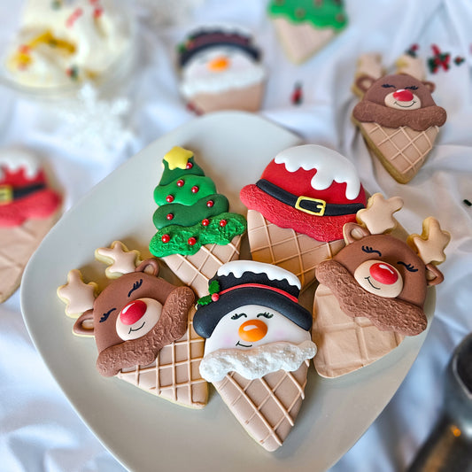 Decorative cookies shaped like ice cream cones with Christmas-themed designs on a white plate.