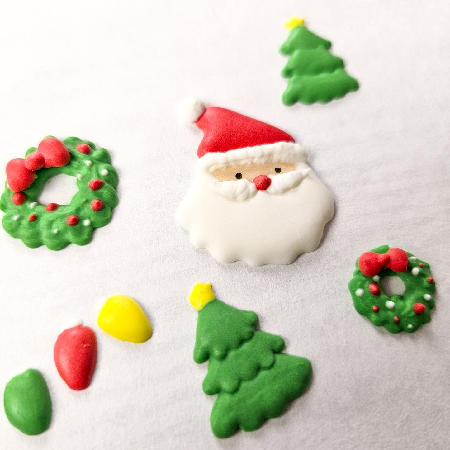 A variety of Christmas themed royal icing transfers including Santa, a wreath, Christmas trees, and Christmas lights