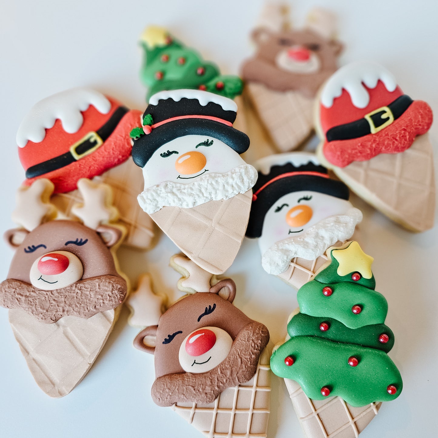 Decorative Christmas-themed cookies shaped like ice cream cones with various characters on a white background.