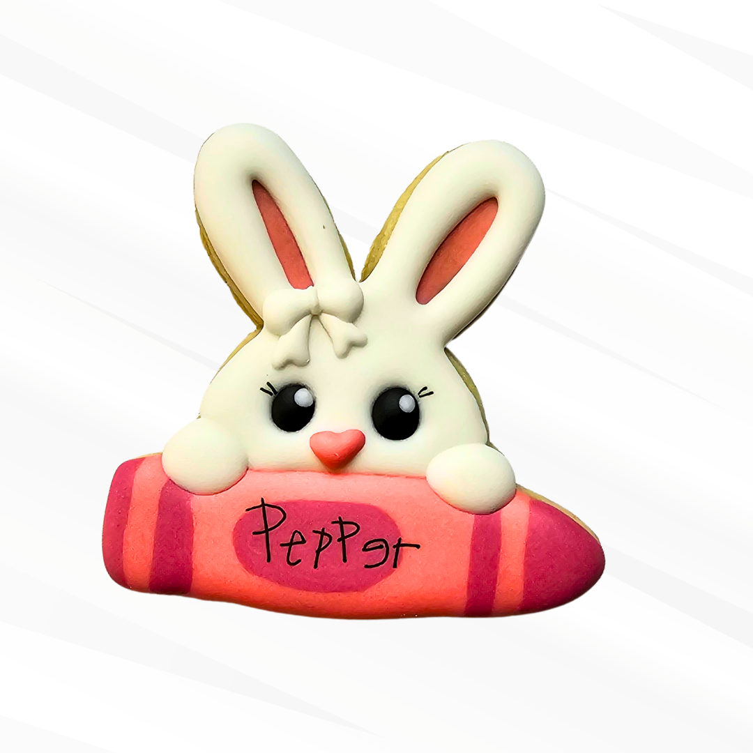 Sugar cookie showing a bunny peeking over a pink crayon