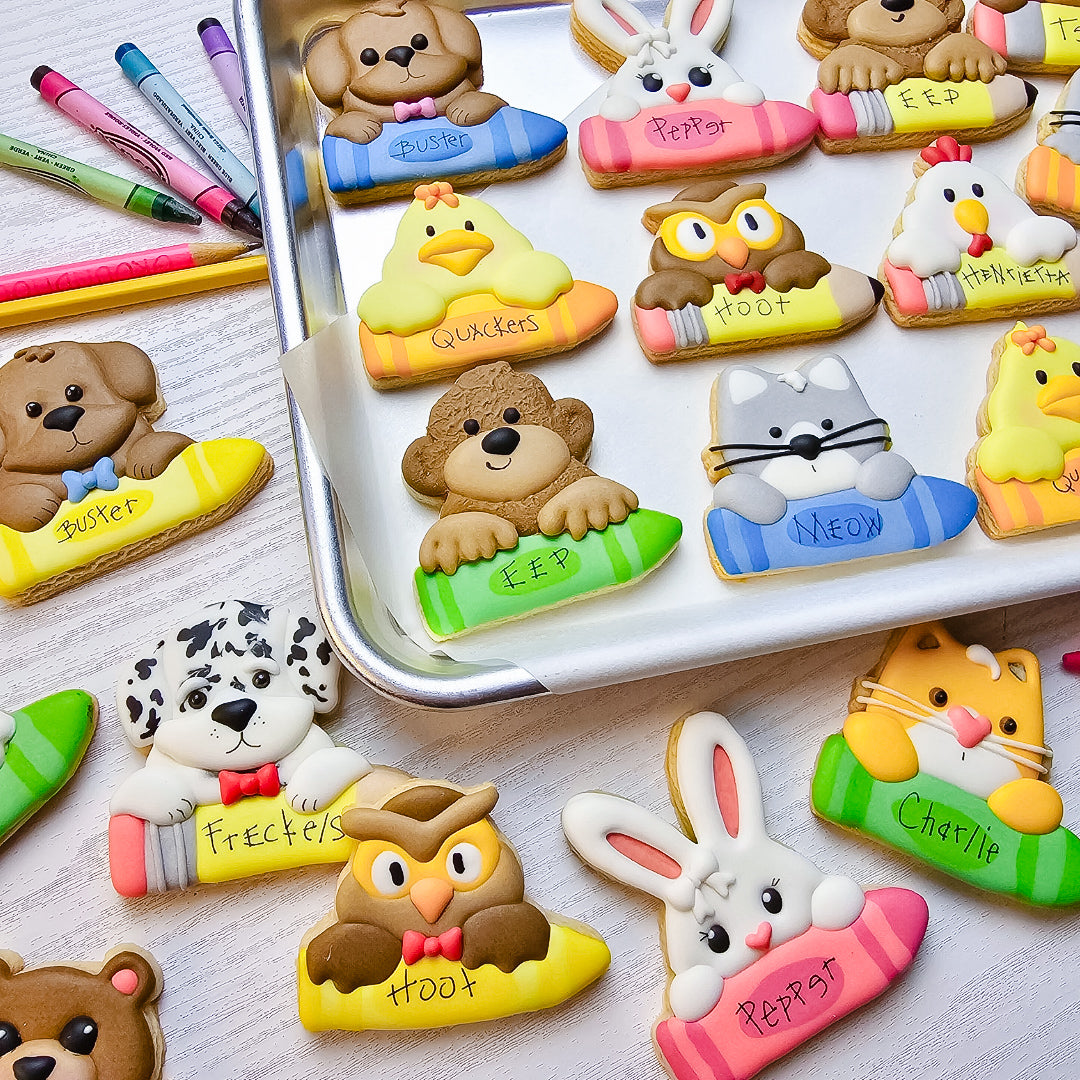 Sugar cookie animals holding pencils and crayons