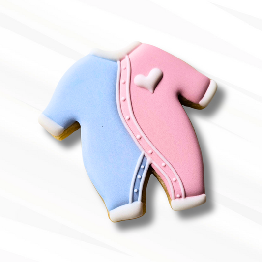 Decorative sugar cookies shaped like baby onesies in pink and blue on a white background