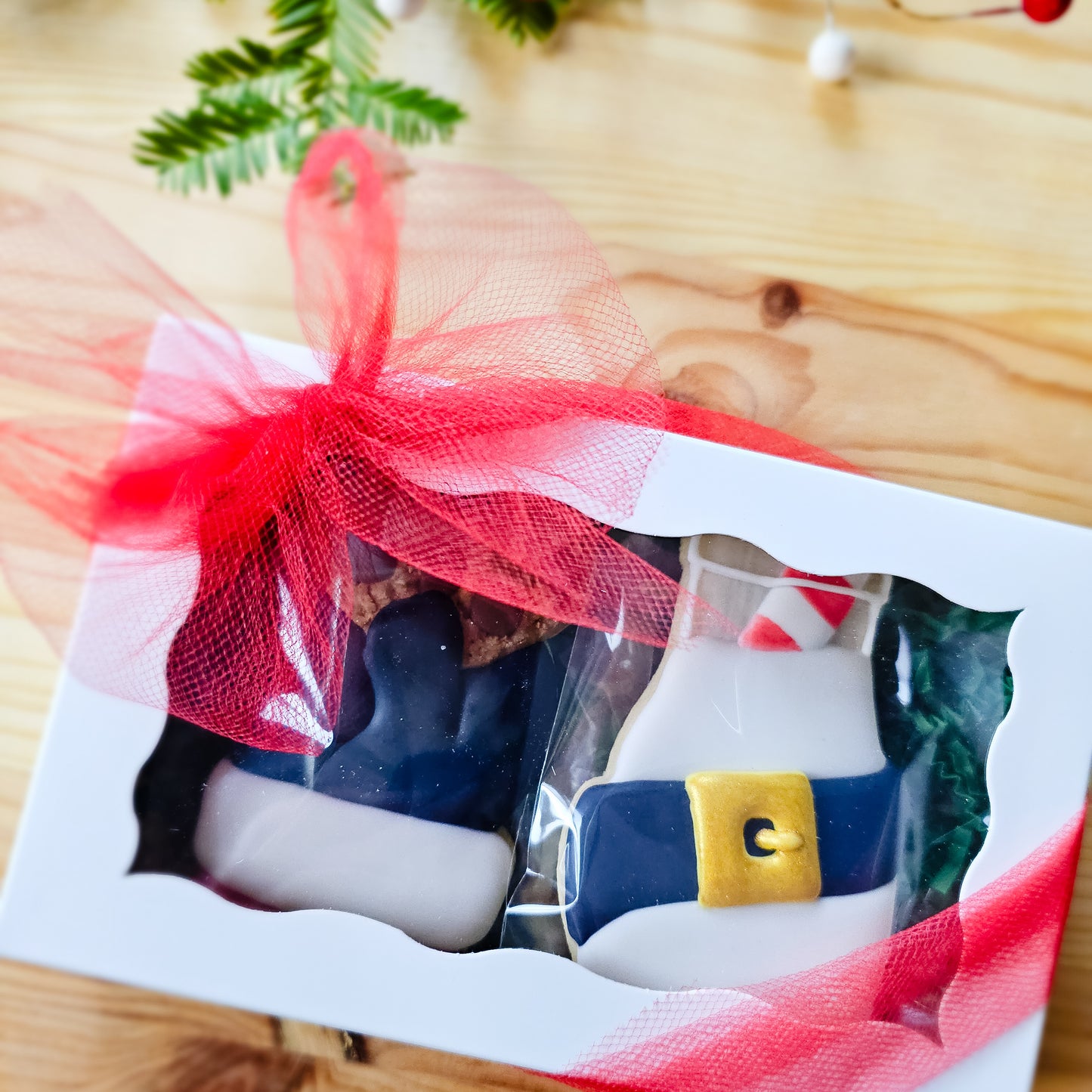 Two Christmas sugar cookies in a white box all tied up in a bow