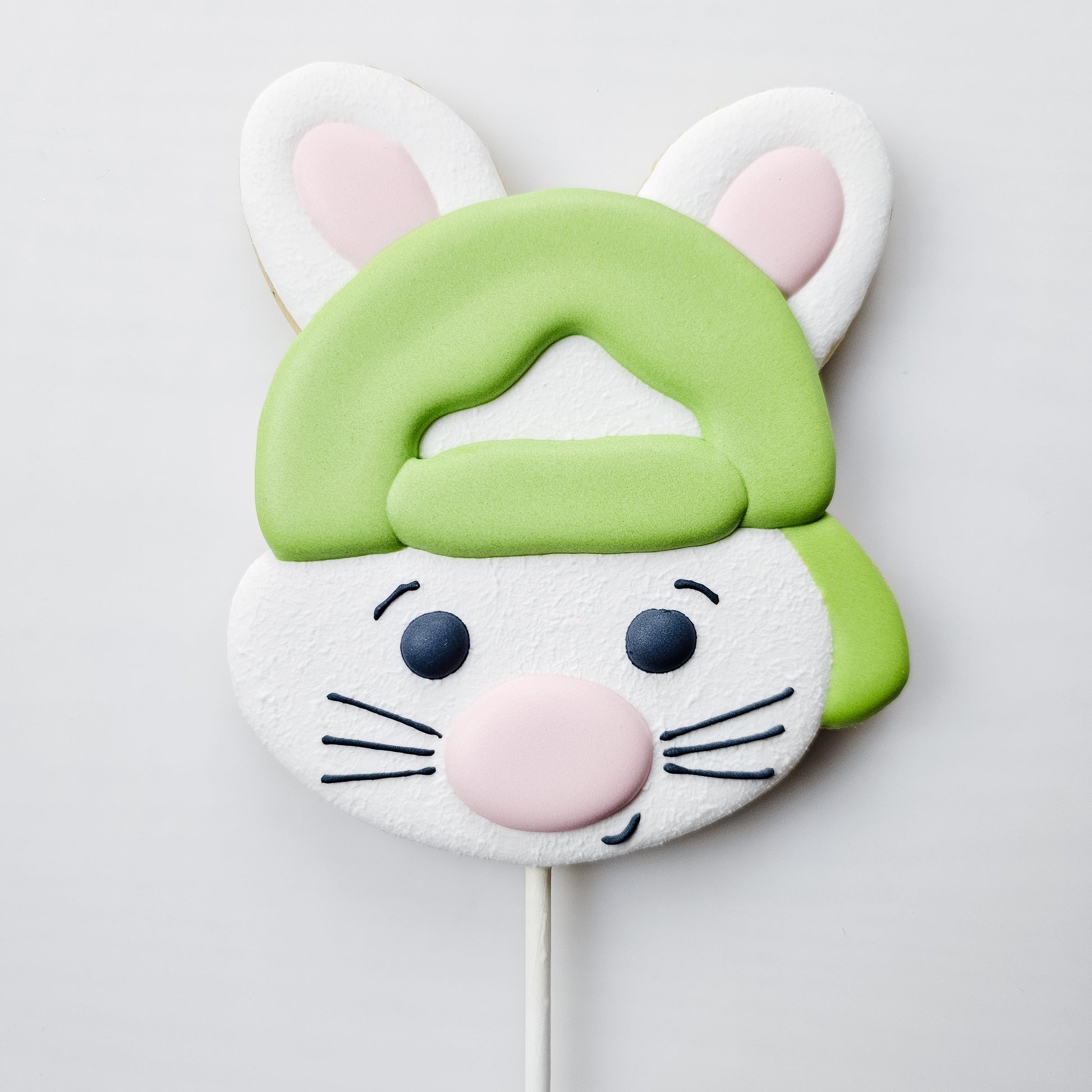 Decorated boy Bunny pop sugar cookie in a green cap on a white background 