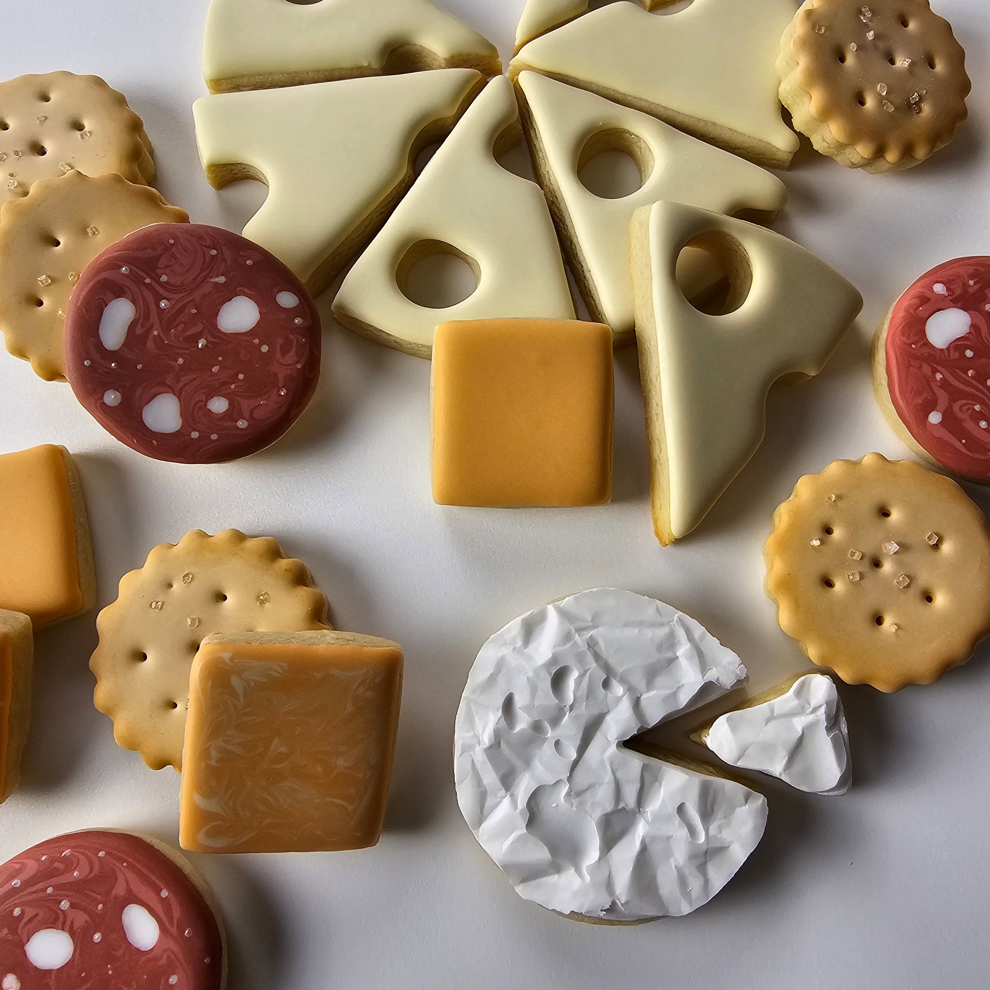 Decorated cookies to look like swiss cheese, colby cheese, cheddar cheese, brie, crackers and salami