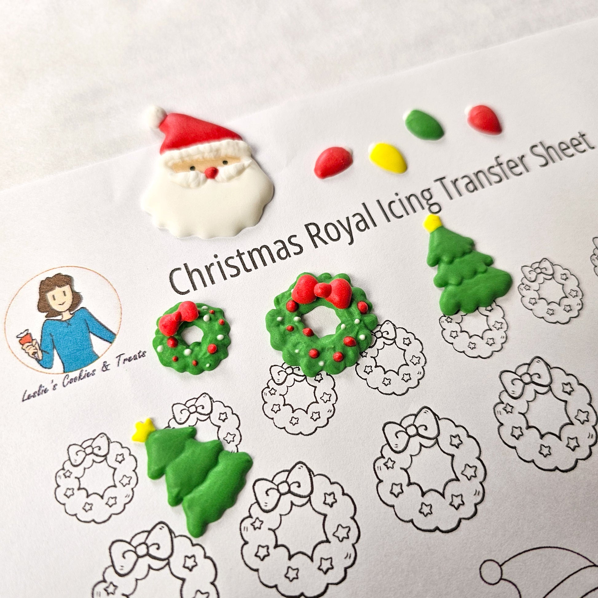 A variety of Christmas royal icing transfers including santa, a wreath, Christmas trees, and Christmas lights
