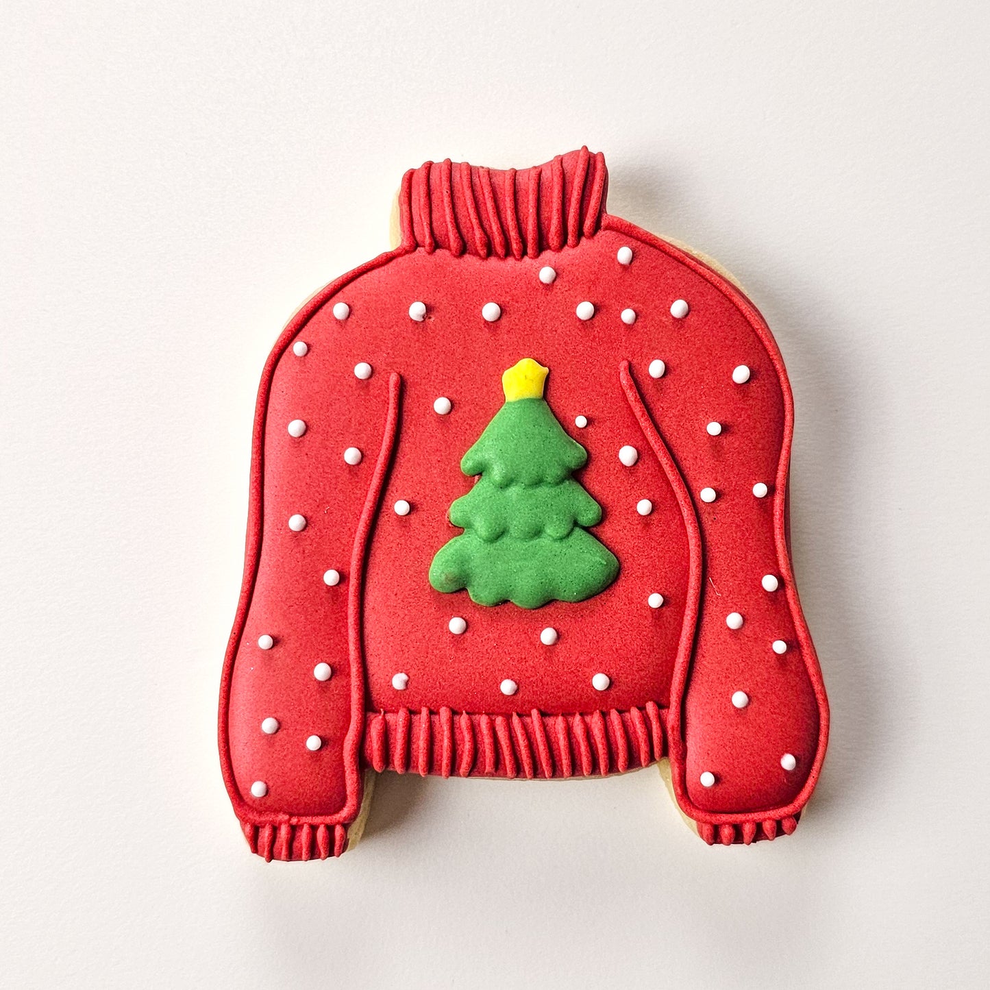 Sugar Cookie shaped like a red sweater with a green Christmas tree on a white background