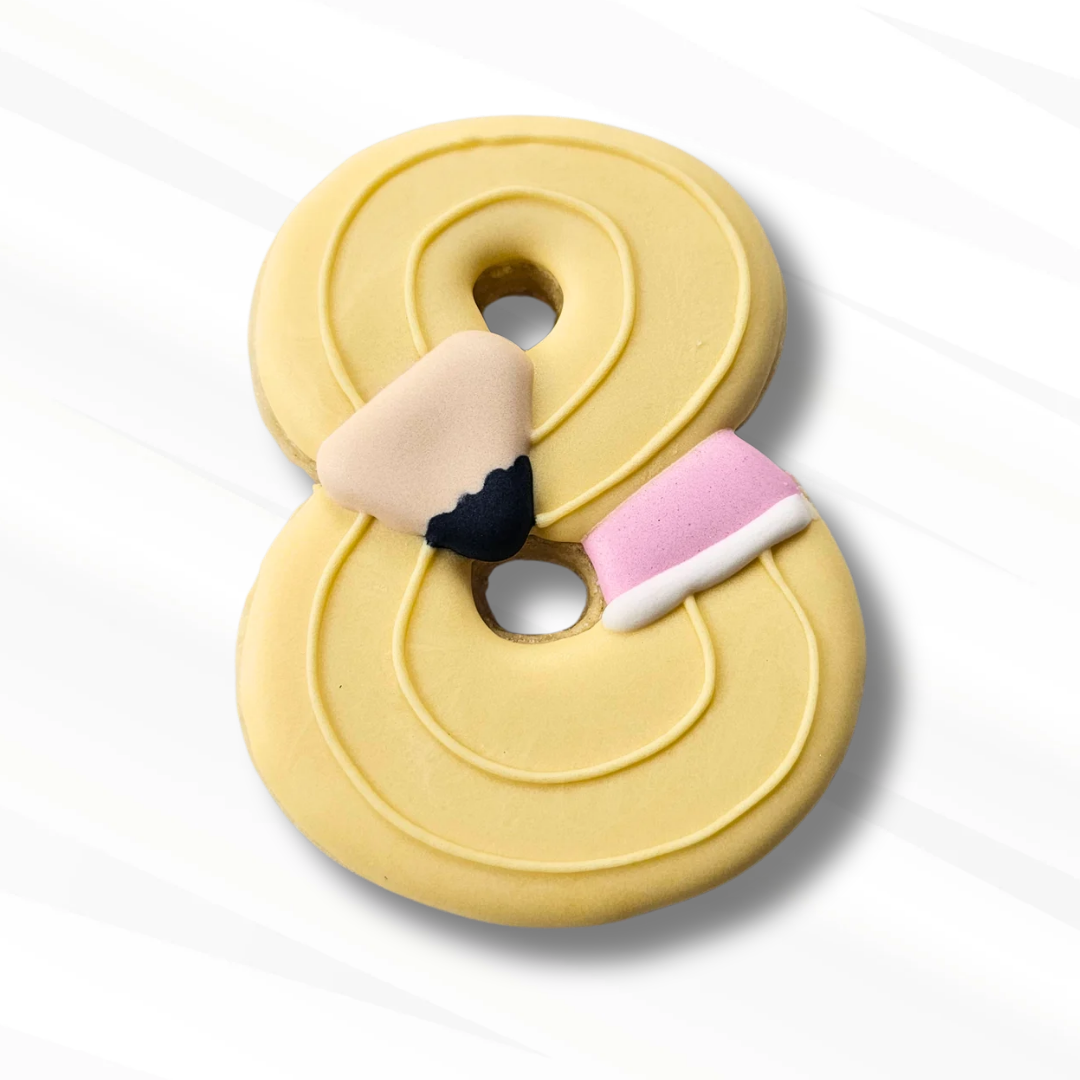 A pale yellow number 8 sugar cookie decorated to look like a pencil on a white background.