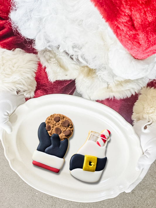 Santa holding a plate with 2 Christmas themed sugar cookies