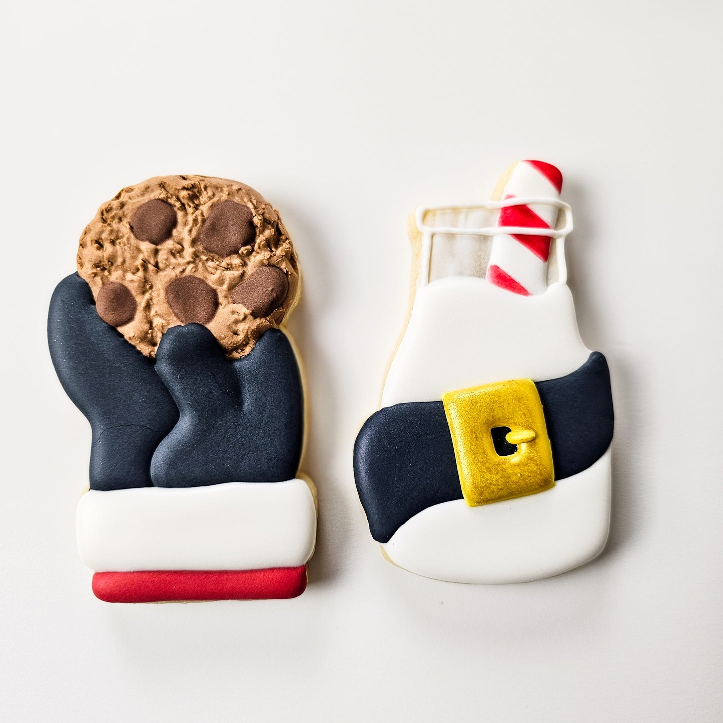 Decorated cookies showing Santa's hand holding a cookie and a bottle of milk wrapped in Santa's belt