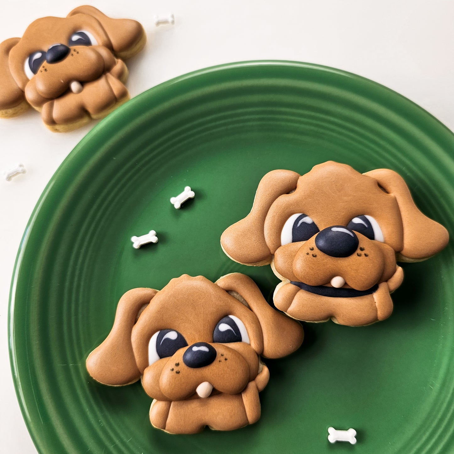 Cute dog sugar cookies on a green plate with bone sprinkles 
