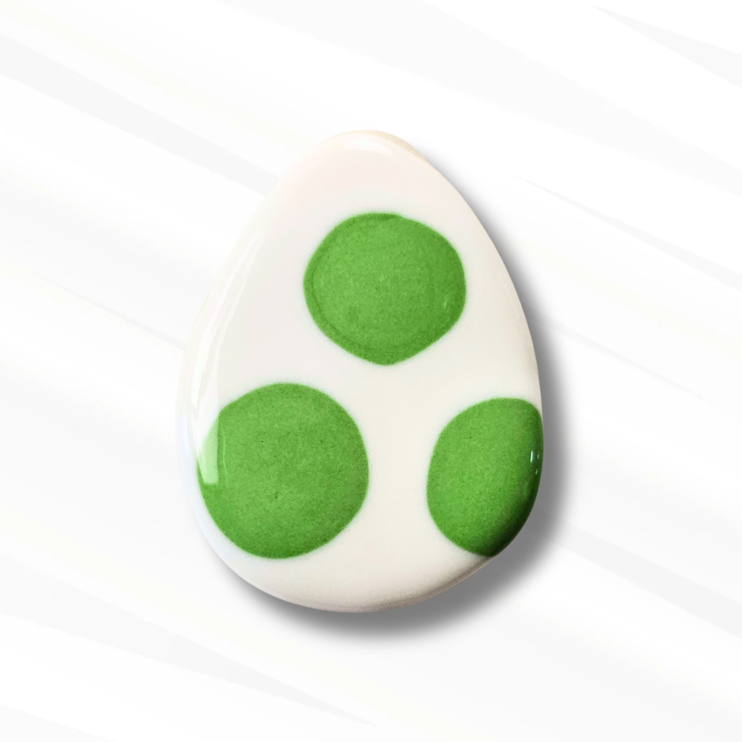 Egg shaped sugar cookie decorated in white with large green spots