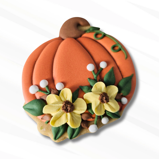 An orange floral pumpkin sugar cookie decorated with yellow flowers, green leaves, small white berries, and a brown stem, shown on a clean white background.