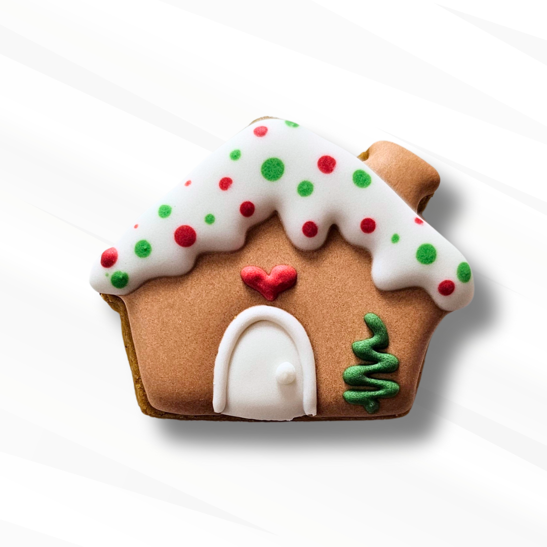 Gingerbread house sugar cookie with icing decorations on a white background