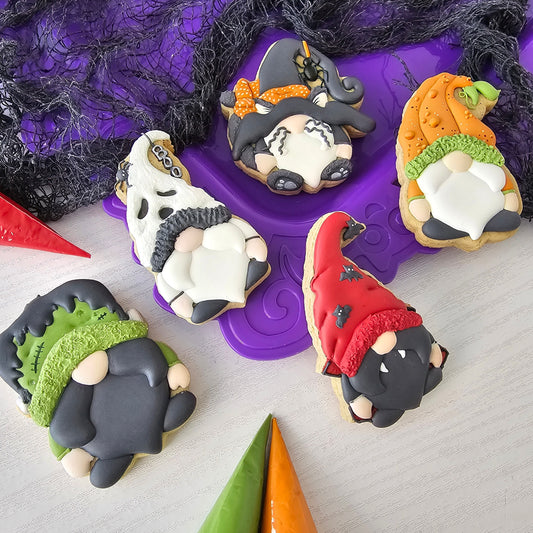 Halloween-themed cookies shaped like gnomes, ghosts, and pumpkins on a purple stand.
