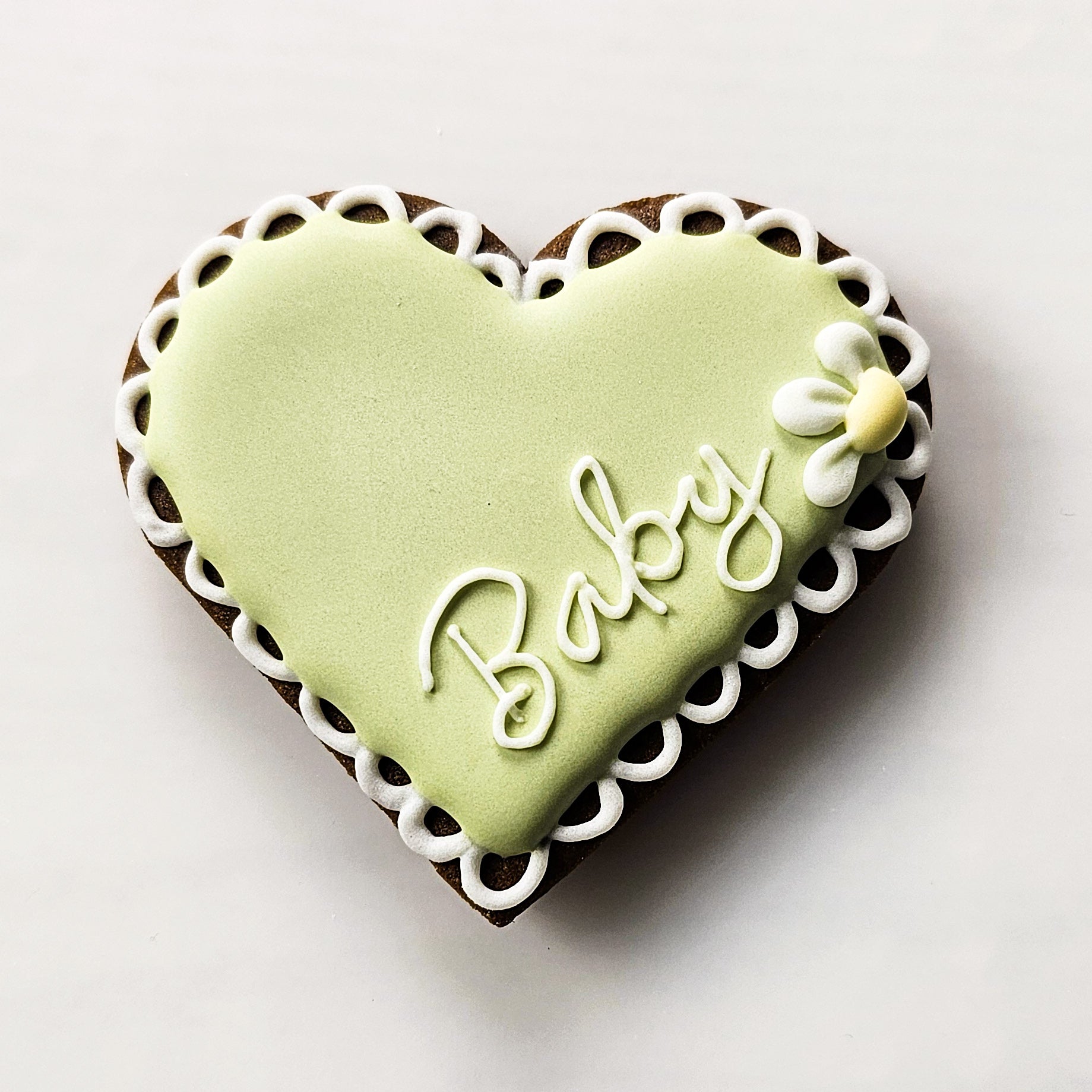 Heart-shaped sugar cookie with 'Baby' written on a white background