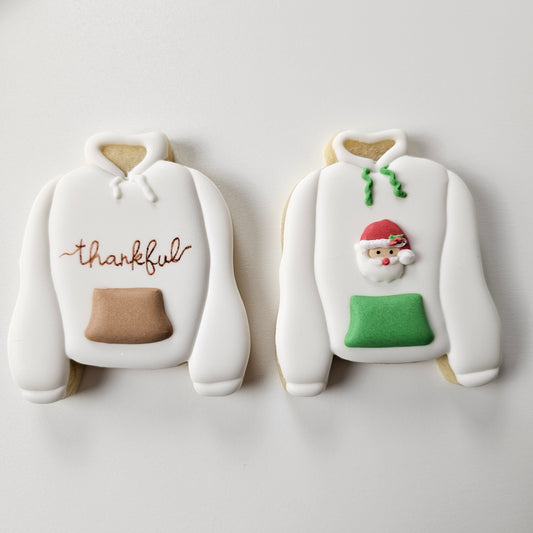 Decorative cookies shaped like a hoodie with a snowman and 'thankful' text on a white background