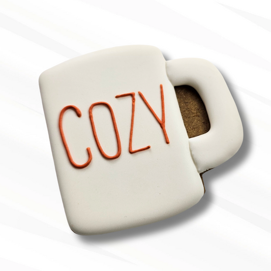 White mug-shaped sugar cookie with 'COZY' text on a white background