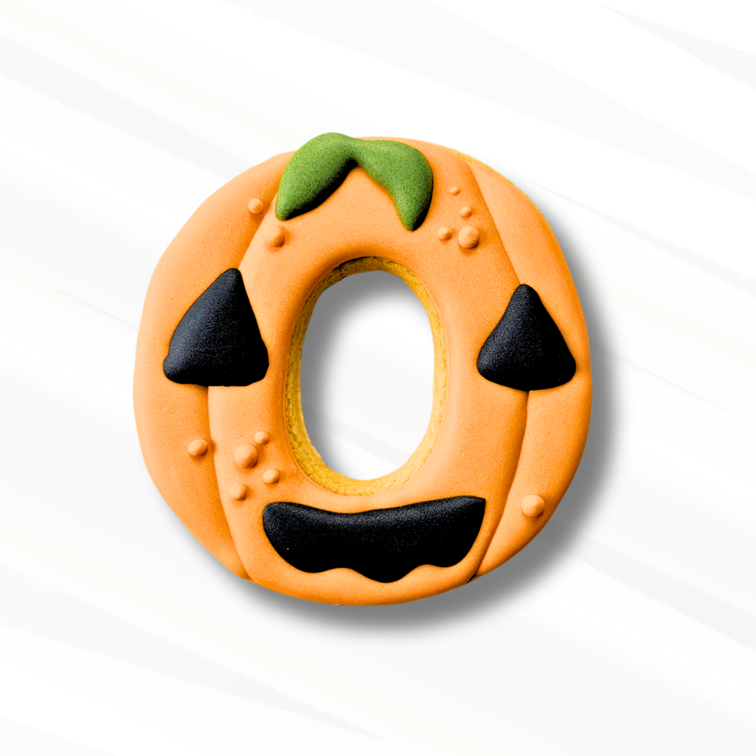 Number 0 sugar cookie decorated to look like a Jack-O-Lantern on a white background