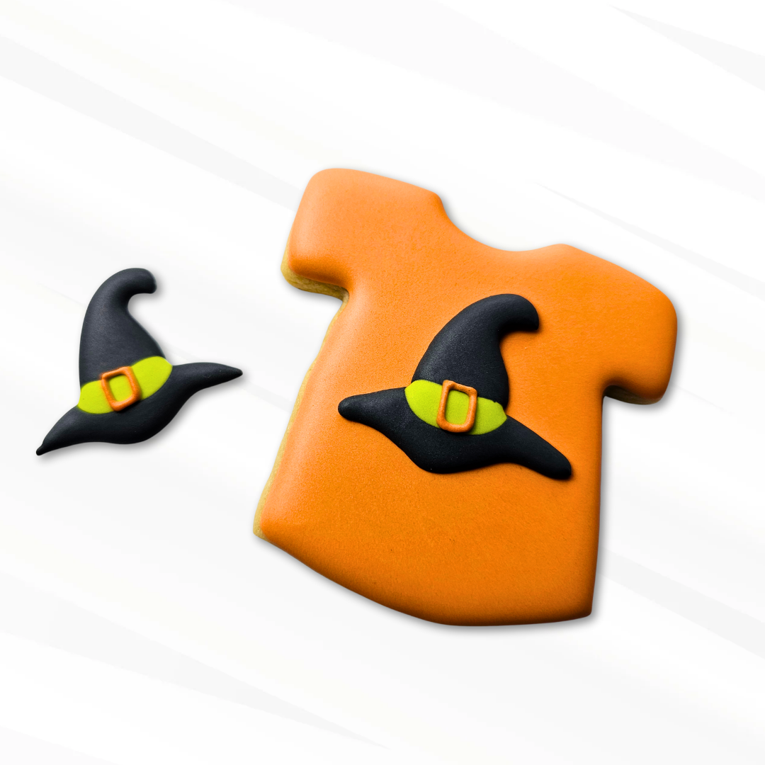 Decorative orange sugar cookie T-shirt with a witch hat royal icing transfer on a white background