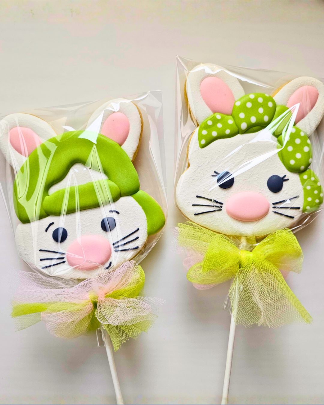 Bunny pop sugar cookies packaged and tied with a green and pink bow on a white background 