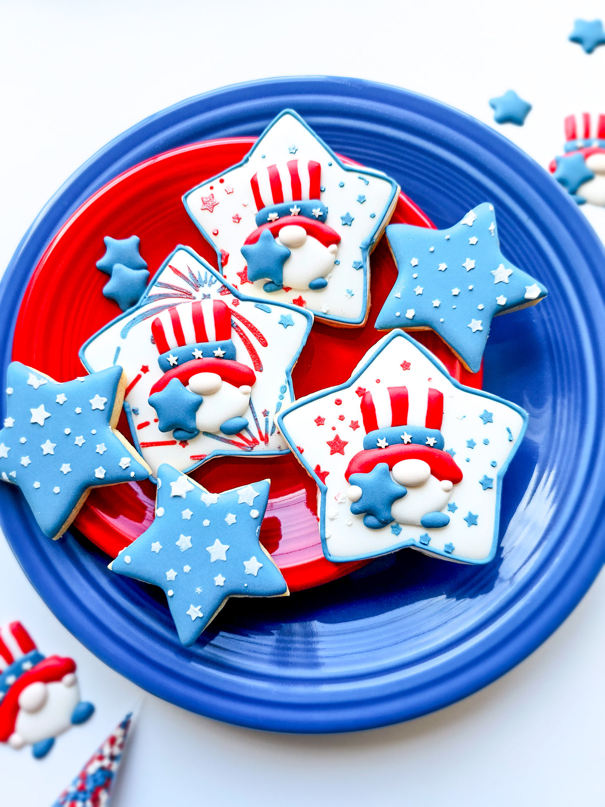 Patriotic gnome royal icing transfers on top of a stenciled star-shaped sugar cookie