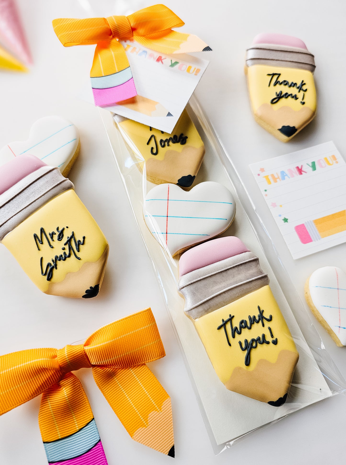 Pencil and notepaper decorated sugar cookies in a decorative package with a pencil bow