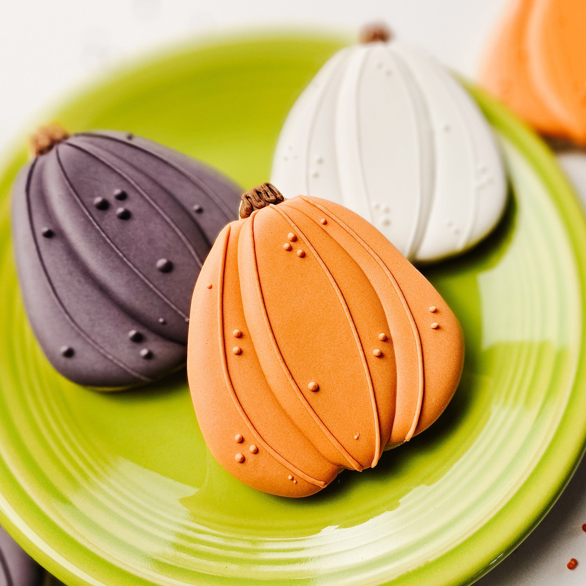 3 pumpkin sugar cookies on a green plate