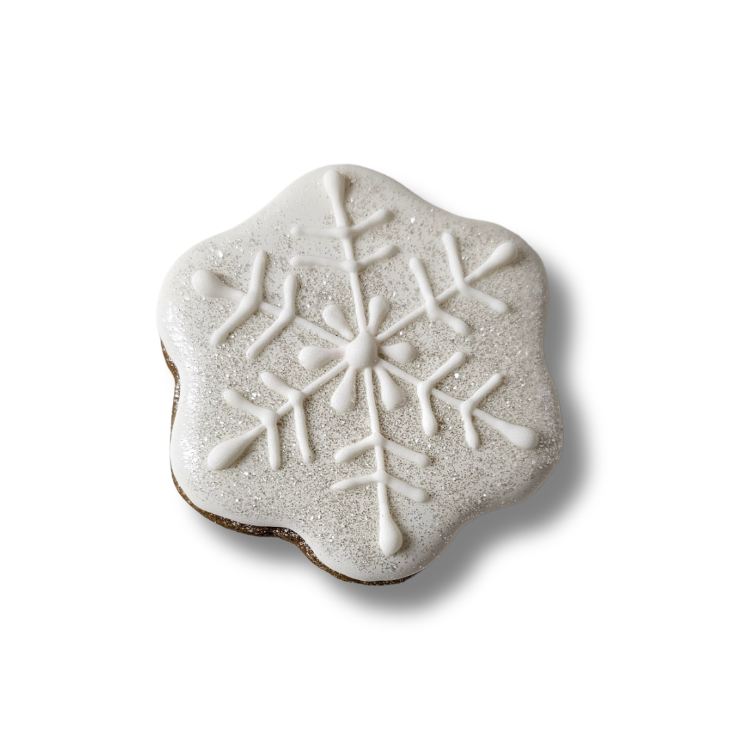 Snowflake-shaped sugar cookie with white icing on a white background