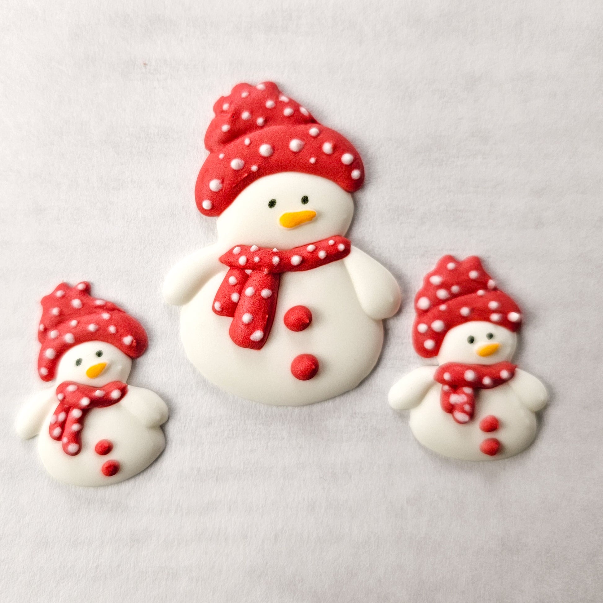 Three snowman royal icing transfers with red hats and scarves