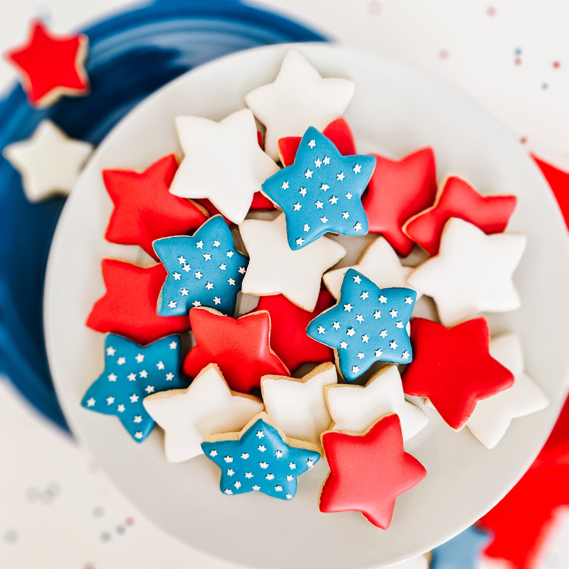 Star-shaped sugar cookies in red, white, and blue on a plate.