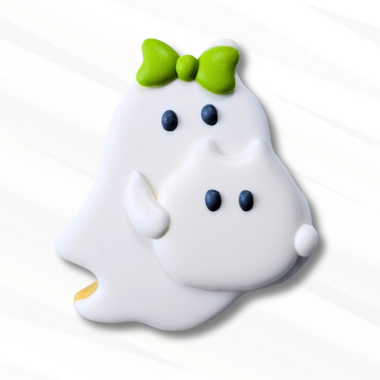 Ghost sugar cookie wearing a green royal icing transfer bow and holding a royal icing transfer ghost cat