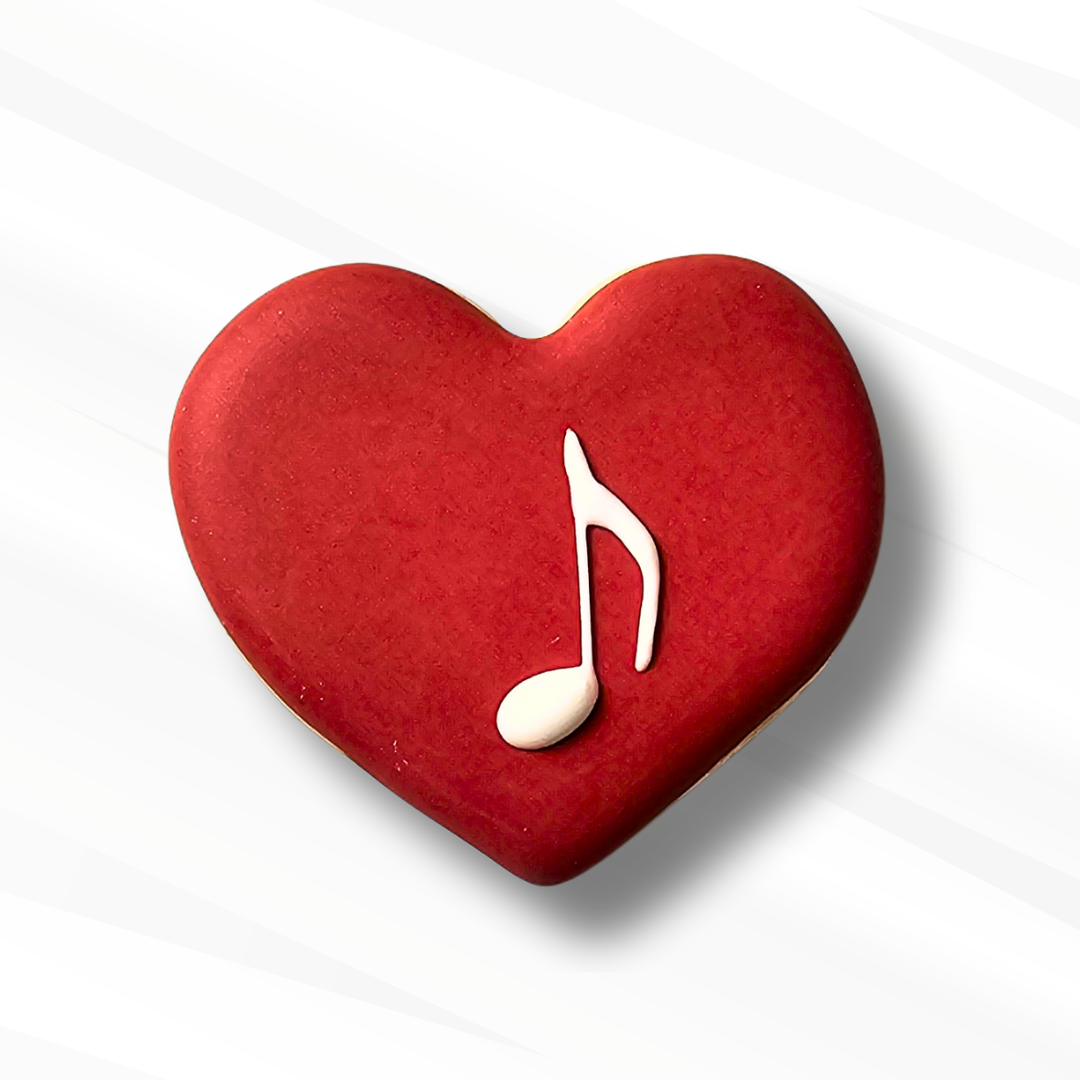 red heart shaped sugar cookie with a music note piped in royal icing