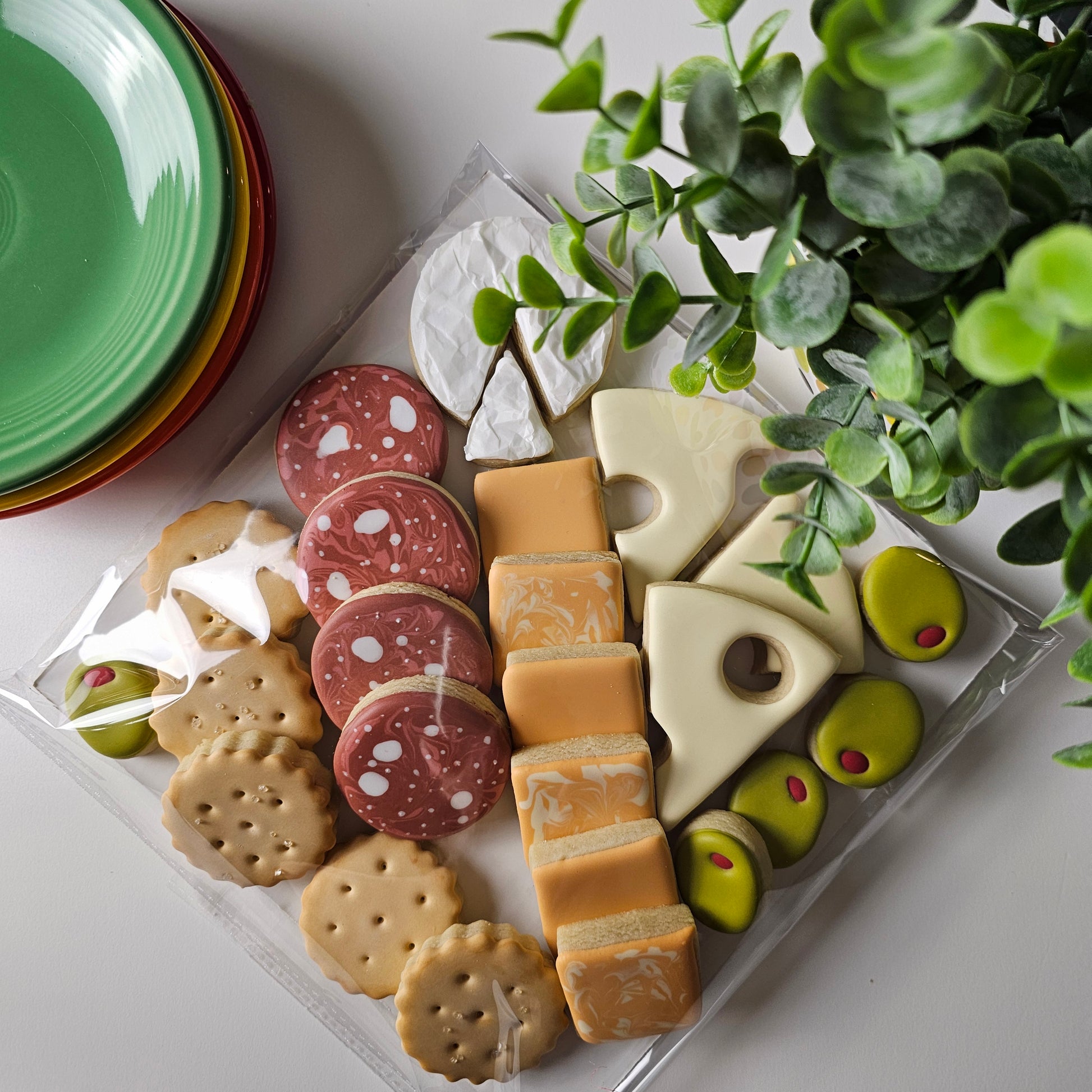 Packaged charcuterie cookie board showing cracker cookies, salami cookies, olive cookies, and a variety of cheese cookies