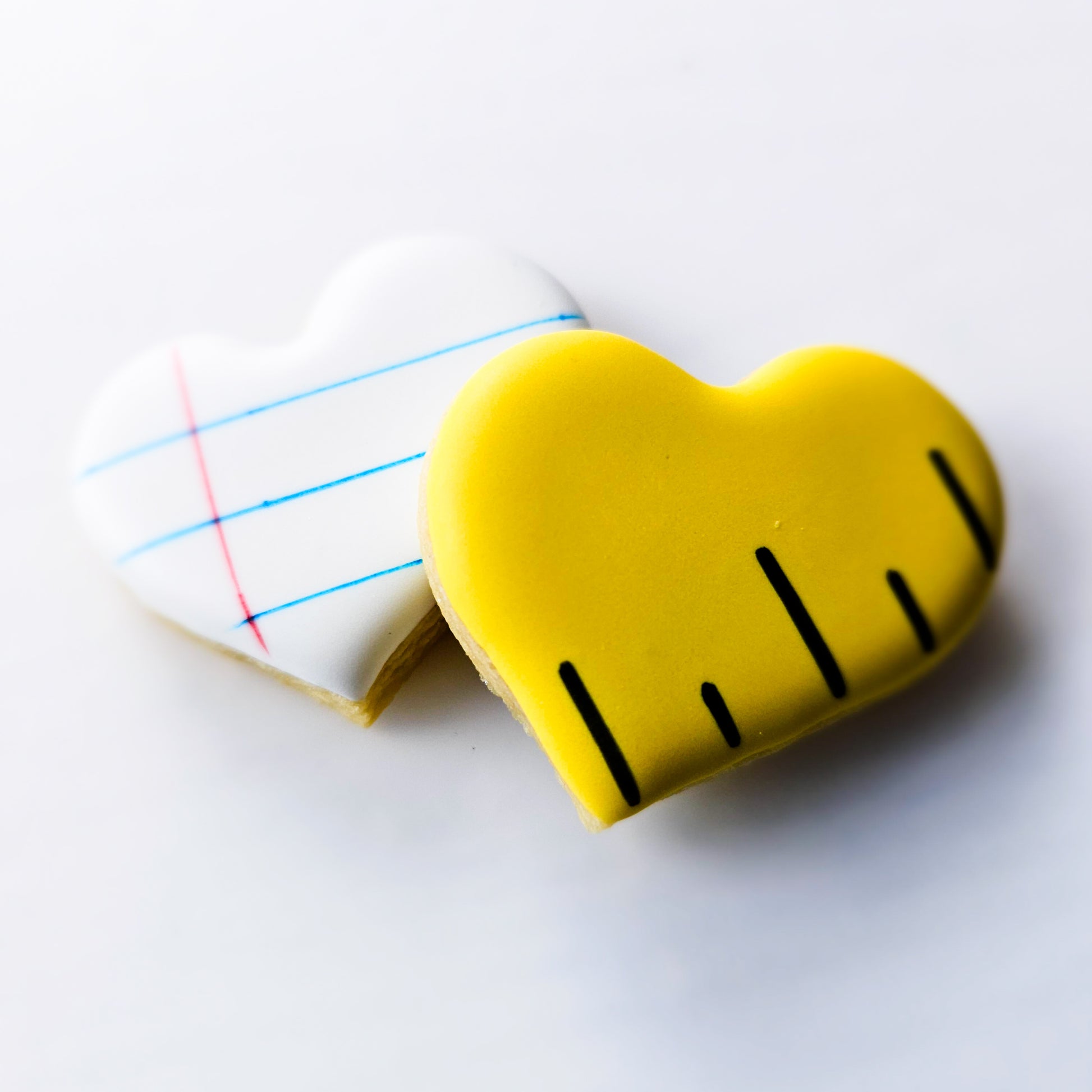 Heart-shaped sugar cookies with a ruler design and a notepaper design on a white background