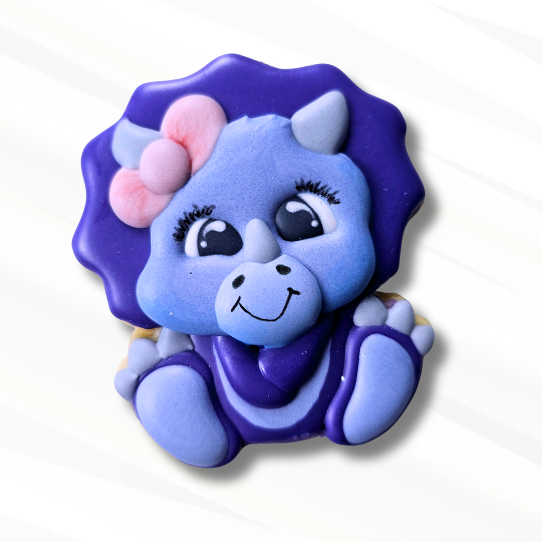 Purple triceratops dinosaur sugar cookie with a pink bow on a white background